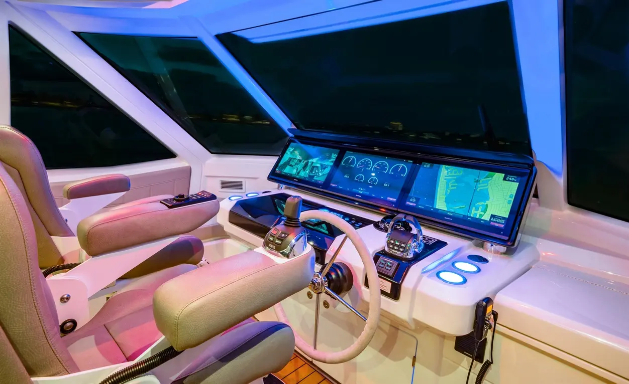 Interior view of a modern boat's control panel with digital displays, steering wheel, and ergonomic seating.